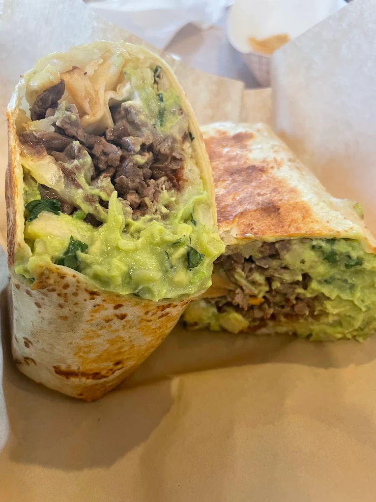 Two grilled burrito halves showing carne asada and guacamole