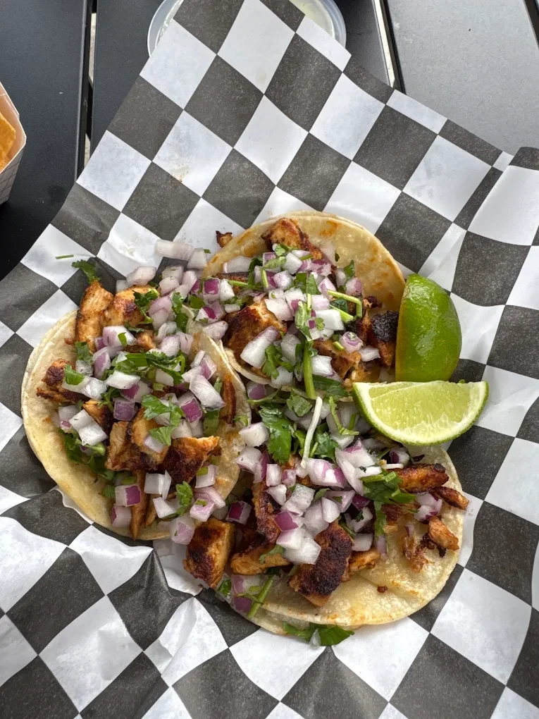Three street tacos with lime on checkered paper