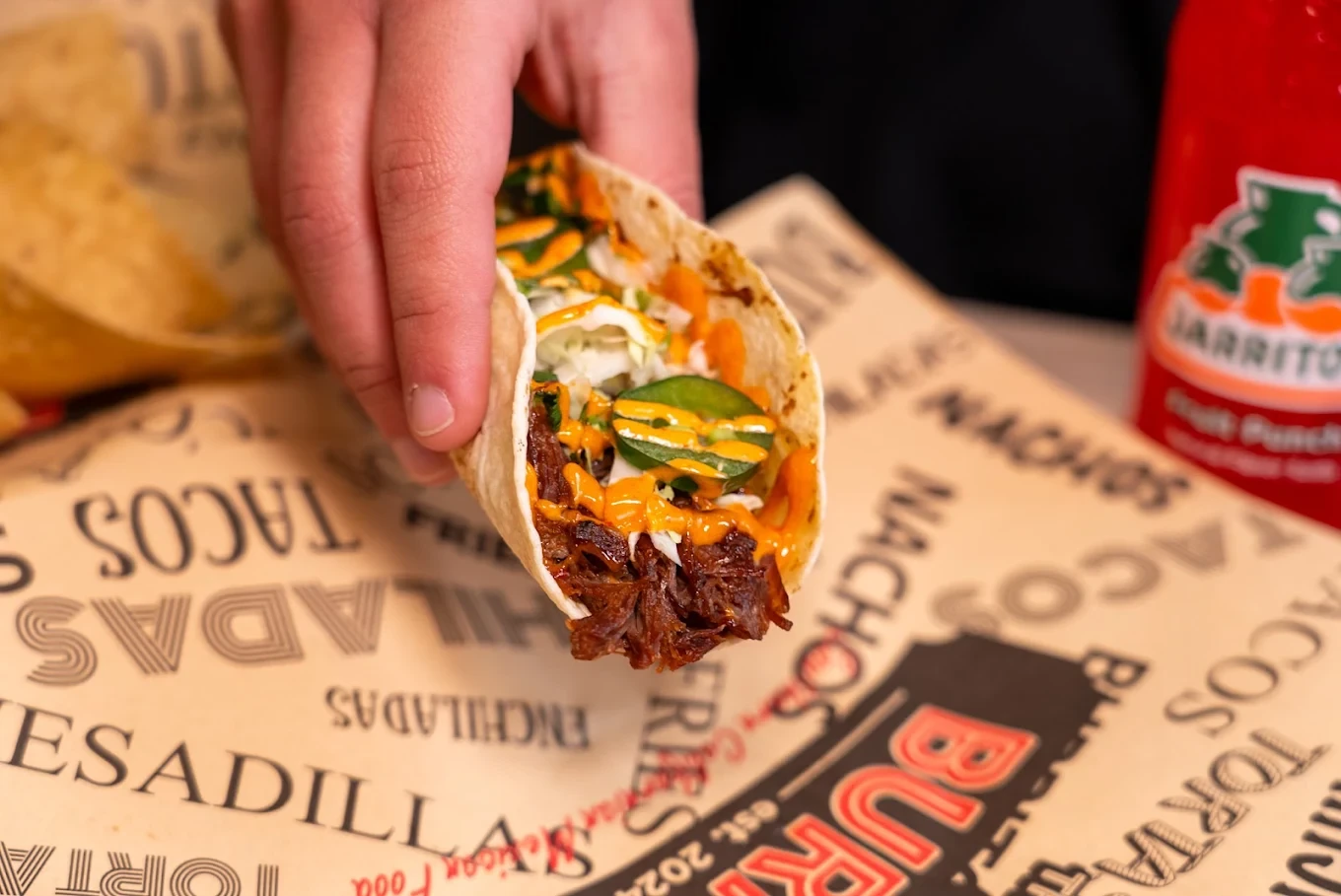 A freshly made taco held over The Salty Burrito counter paper